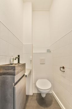 The interior of the bathroom is lined with white tiles, which has a marble sink and a hinged toilet