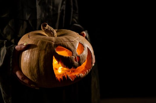 The witch is holding a pumpkin jack o lantern glowing in the dark. Halloween