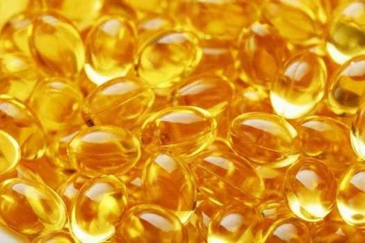 The texture of the capsules in the shell with liquid vitamin D3 in full screen. Gold capsules with a dietary supplement for joints teeth and bones.