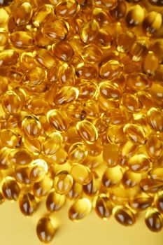 The texture of the capsules in the shell with liquid vitamin D3 in full screen. Gold capsules with a dietary supplement for joints teeth and bones.