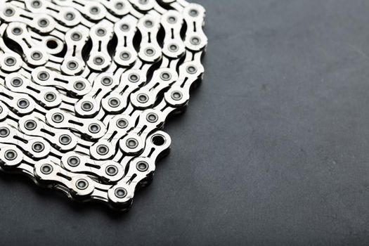 Silver chain of a road bike on a dark textured background with free space