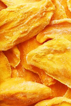 Dried sweet mango fruit slices as textural orange background in full screen