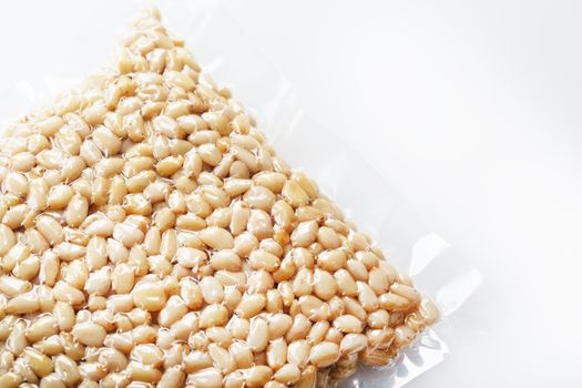 Pine nuts in a transparent vacuum package over a white background