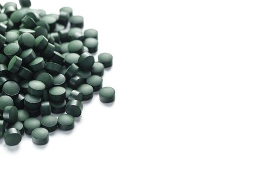 Vegetarian vitamins from Spirulina are scattered on a white background with free space