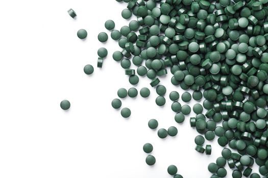 Vegetarian vitamins from Spirulina are scattered on a white background with free space