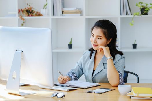 Young economists or accountants or financiers and investors are reviewing budget documents and using computers to study impact and risk assessments on corporate investment management