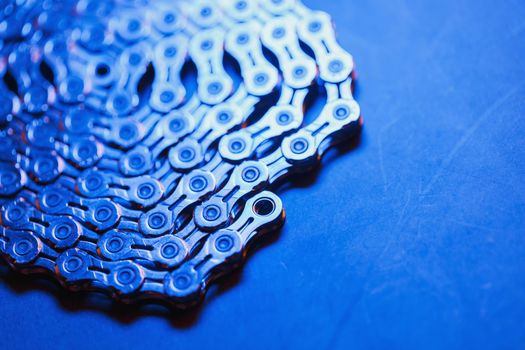 Patterns of a technological bicycle chain braided in a circle with blue-purple illumination