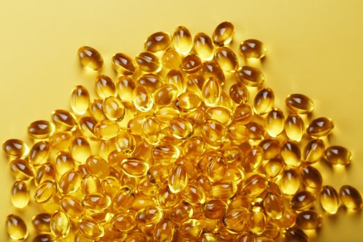 The texture of the capsules in the shell with liquid vitamin D3 in full screen. Gold capsules with a dietary supplement for joints teeth and bones.