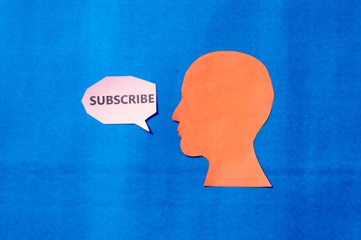 Paper Human face with Subscribe word on speech bubble isolated on blue background. Copy Space for text.