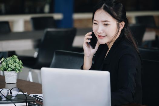 A female business woman is using the telephone to communicate with colleagues for financial planning and investment planning