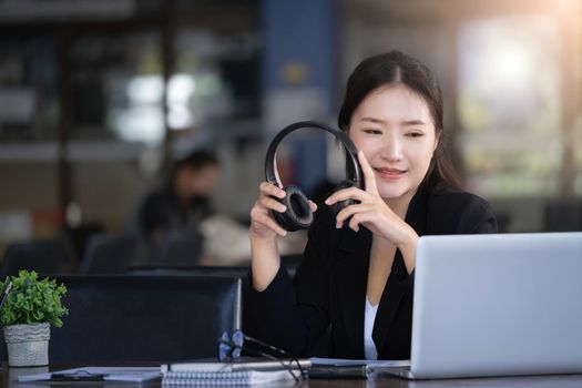 Concept of taking a break from work, an accountant or a female company employee or a business owner is using headphones to listen to music to relieve stress and fatigue from work