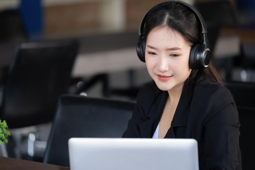 Concept of taking a break from work, an accountant or a female company employee or a business owner is using headphones to listen to music to relieve stress and fatigue from work