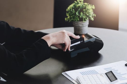 Safe technology concept from using credit card, employee is holding customer's credit card to pay for service or payment via electronic card swipe machine