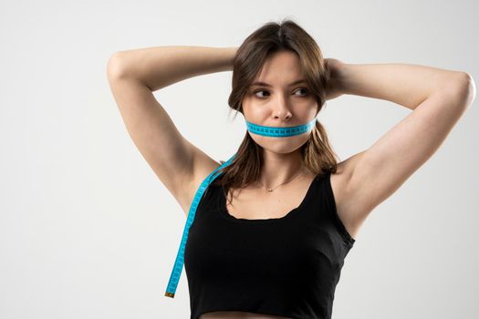 Confused brunette woman in a black underwear holding measuring tape around her mouth. Weight loss, slim body, healthy lifestyle concept