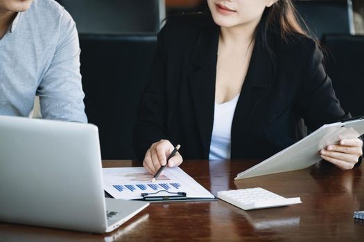 Teamwork concept, consultation, male economist holding pen pointing to budget, finance and investment documents, discussing and planning finances with female advisors in conference room