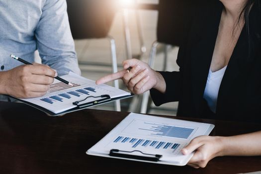 Teamwork concept, consultation, male economist holding pen pointing to budget, finance and investment documents, discussing and planning finances with female advisors in conference room