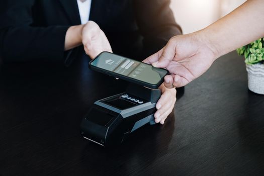 Payment security technology concept and service fees, Employees are holding electronic card machines for customers to use smartphone mobile to pay via paywave technology