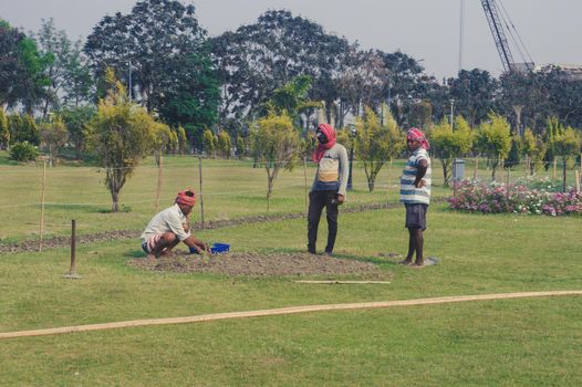 Four men professional Gardeners weeding and gardening in a garden of a public park. Eco Park, New Town 25 March 2022