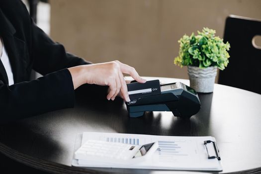 Safe technology concept from using credit card, employee is holding customer's credit card to pay for service or payment via electronic card swipe machine