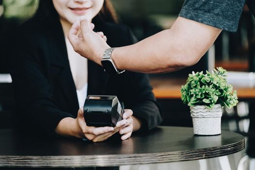 Payment security technology concept and service fees, Employees are holding electronic card machines for customers to use smartwatches to pay via paywave technology