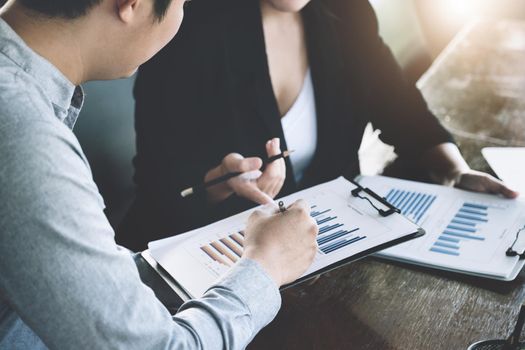 Teamwork concept, consultation, male economist holding pen pointing to budget, finance and investment documents, discussing and planning finances with female advisors in conference room