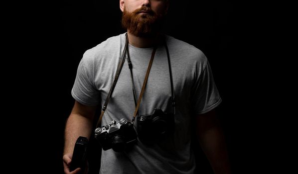 Professional photographer in a grey t-shirt with a bunch of different cameras on a shoulder