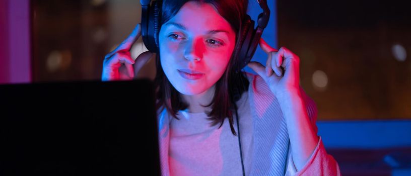 A young girl holds headphones and is listening and composing music, a woman sits with a laptop by the window in her room, works and enjoys the sound.