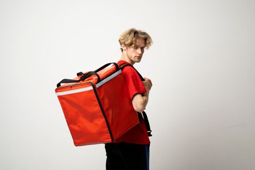 Delivery Service Cocnept. Courier wearing red uniform and thermo backpack bag looking at camera isolated on white studio background