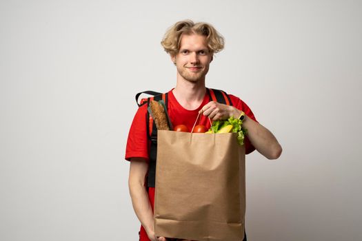 Man holding paper bag with fresh products from a groceries store on white background. Food delivery service