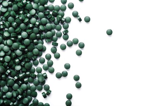 Vegetarian vitamins from Spirulina are scattered on a white background with free space