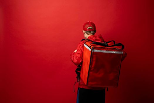 Delivery man in red uniform with a thermal backpack isolated on a white background. Fast home delivery. Online order. Courier delivers groceries home