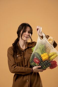 Woman showing a reusable mesh shopping bag full of fresh groceries. Zero waste. Ecologically and environmentally friendly packets. Canvas and linen fabrics. Save nature concept