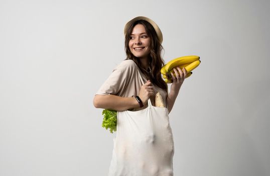 Zero waste concept. Young woman holding reusable cotton shopping bag with groceries from a market. Concept of no plastic. Zero waste, plastic free. Eco friendly concept. Sustainable lifestyle