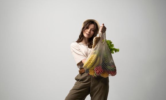 Young brunette woman bought a eco foods in zero waste shop and put it in amesh eco bag. Zero waste. Ecologically and environmentally friendly packets. Vegan Lifestyle Concept