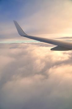 Flying and traveling. View from airplane window on the wing during sunset. Plane over clouds in the sky.