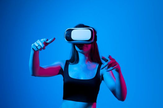 Amazed female in VR glasses headset interacting with network while having virtual reality experience. Future technology concept. Metaverse