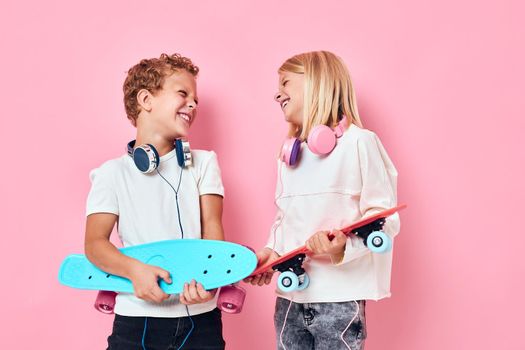 Stylish little boy and cute girl stand next to skateboards active lifestyle childhood. High quality photo