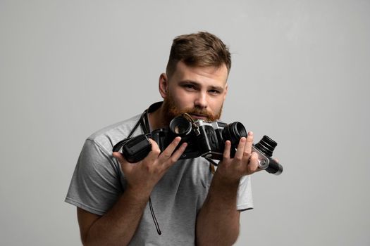 Bearded professional photographer with a bunch of different vintage film cameras in a hands looking on a camera and ready for make a good shoot
