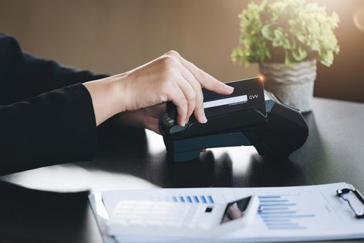 Safe technology concept from using credit card, employee is holding customer's credit card to pay for service or payment via electronic card swipe machine