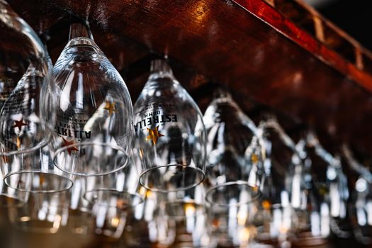 Empty wine glasses hanging on rack in pub bar.