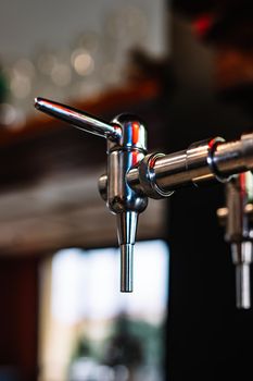 detail of beer dispenser. Apparatus for dispensing beer in the bar. Restaurant. warm atmosphere and dim light. Light reflected on beer dispenser.