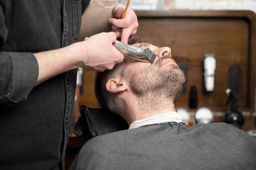 Professional barber cutting beard of handsome man. High quality photography.