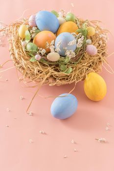 Easter eggs in nest on pink background.
