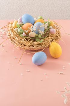 Easter eggs in nest on pink background.