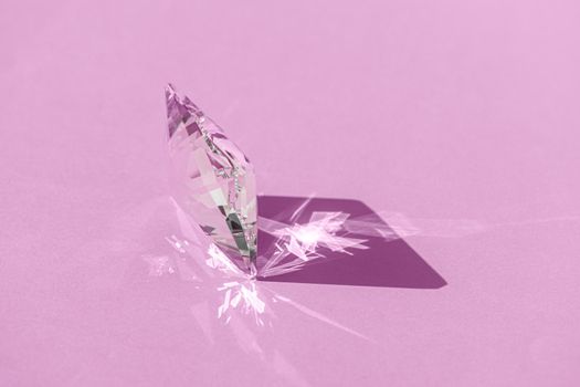 Crystal prism with light diffraction of spectrum colours and reflection with trendy light and hard shadows on pink background. Light spectrum reflected through glass prism. Banner