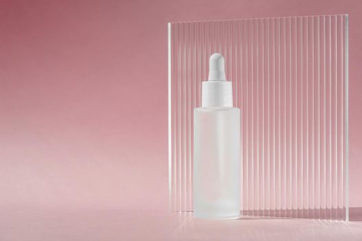 Serum oil with collagen and peptide in white transparent bottle with dropper on pink decor backdrop with acrylic ribbed sheet. Skincare treatment skincare mockup packaging liquid cosmetic product.