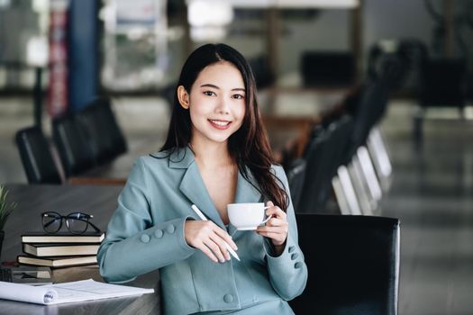 Young economist or accountant or financier and investor is drinking coffee while reading budget documents to study the impact and risk assessment of corporate investment management