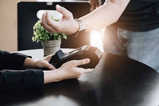 Payment security technology concept and service fees, Employees are holding electronic card machines for customers to use smartwatches to pay via paywave technology