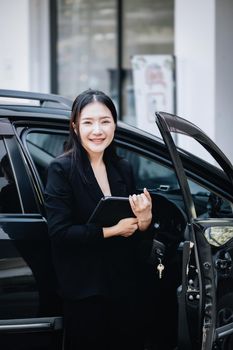 Asian businessmen, business owners, company presidents or female employees holding a tablet are getting out of the car to attend a business plan meeting at the meeting