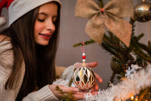 Long sleeves in cream sweater. Christmas tree bauble in delicate feminine hands. An annual Christmas decorating ritual in Poland.